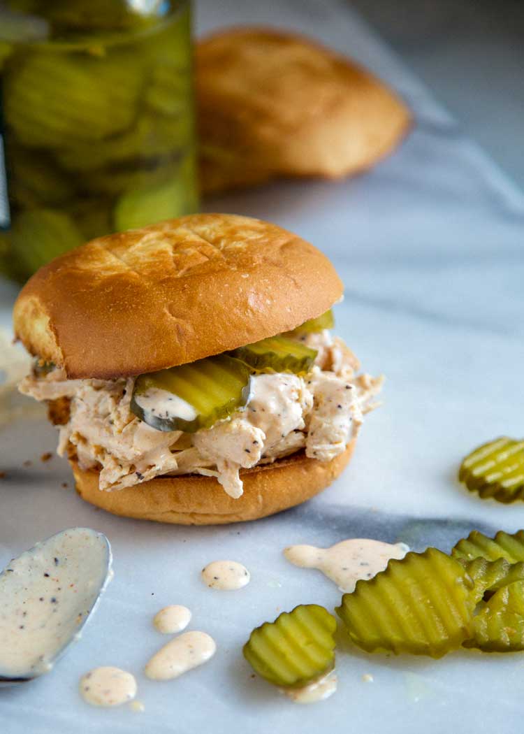 chicken and pickles with white sauce on a toasted bun