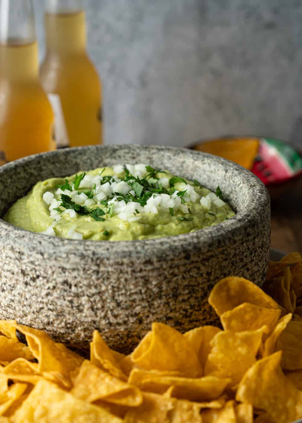 tortilla chips and salsa guacamole on a counter with beers