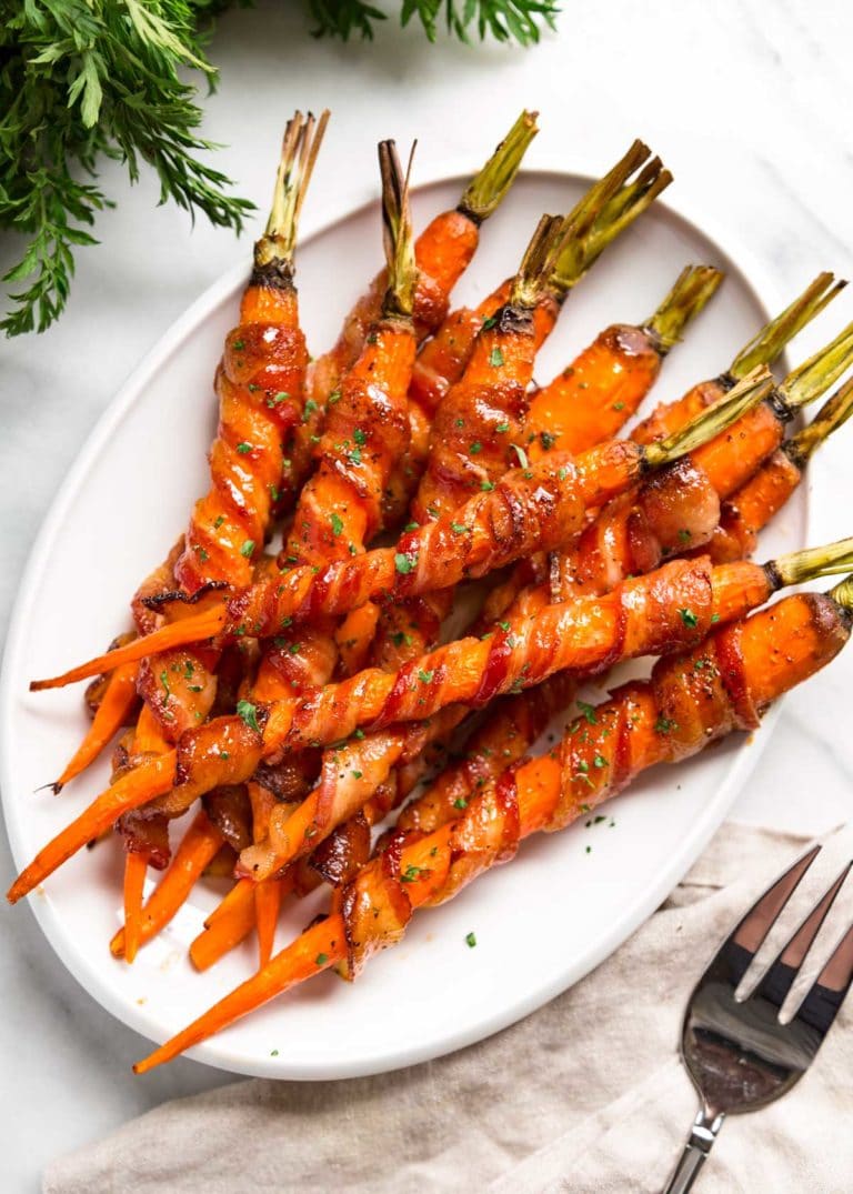 These Bacon Wrapped Carrots get sprinkled with black pepper and roasted, then basted with a maple Sriracha sauce until crispy. So easy and good! keviniscooking.com