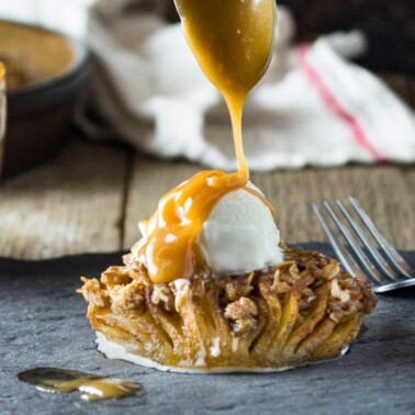 close up: spooning caramel sauce over ice cream on baked apple dessert