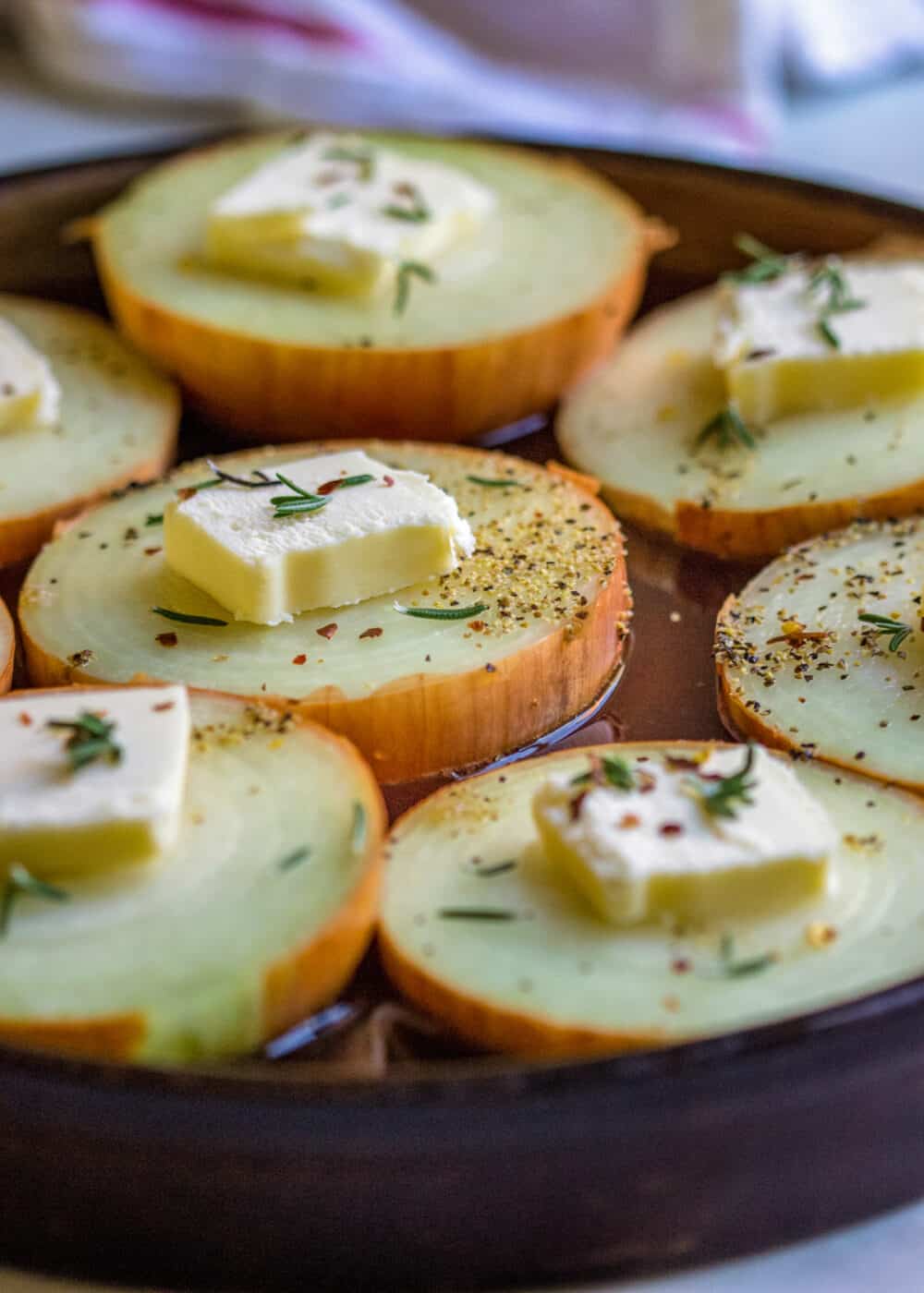 close up: raw vegetable slices in baking dish- pats of butter on top