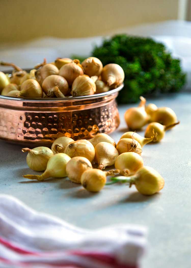 pearl onions in a copper bowl with more on the counter