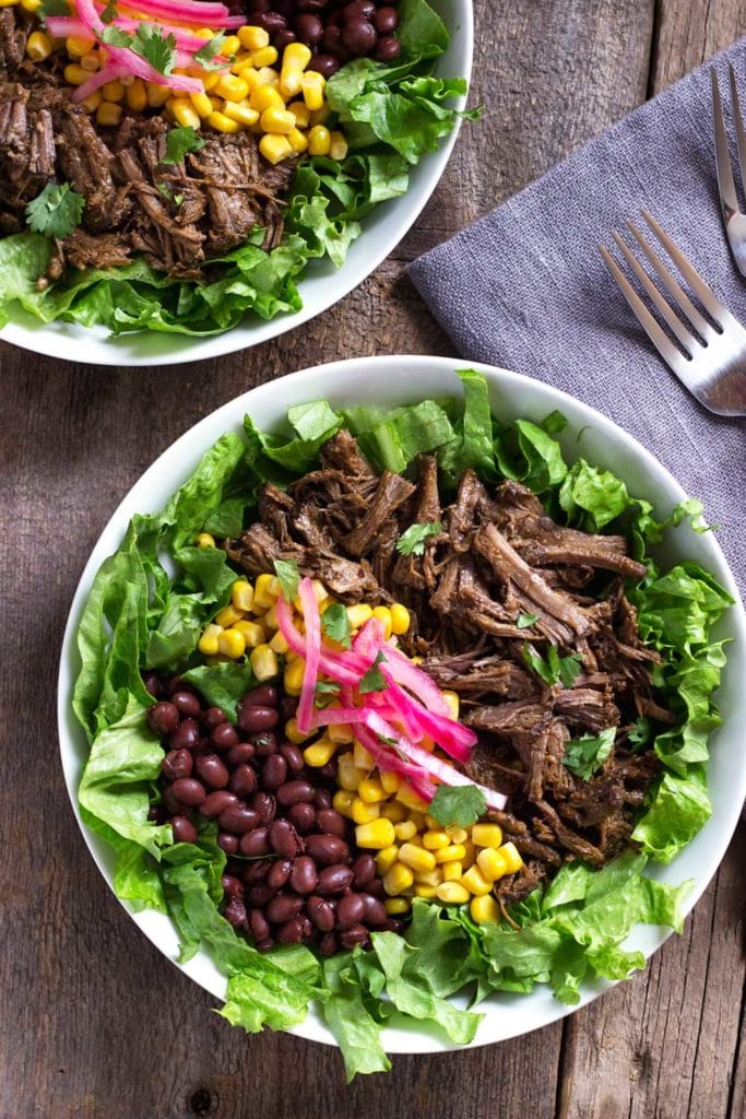 overhead: chipotle barbacoa on salad greens with corn and black beans