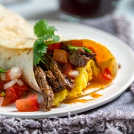 beef barbacoa breakfast burrito on white plate