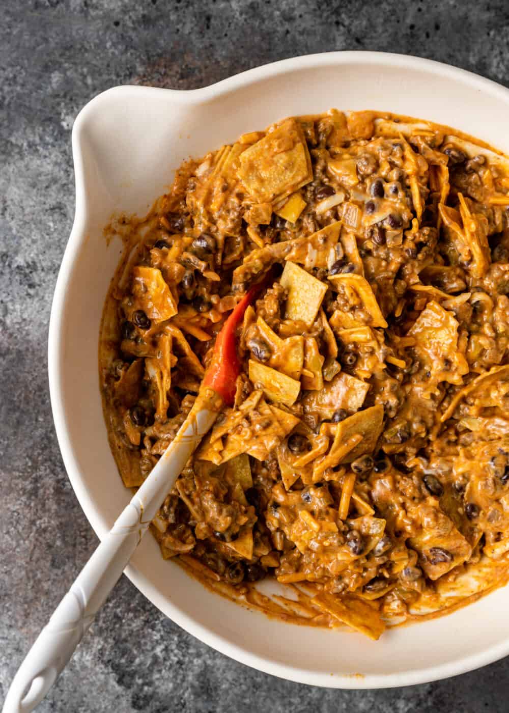 overhead: stirring cheesy beef enchilada casserole mixture in bowl