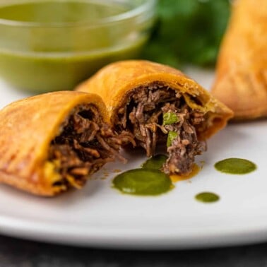 beef empanada cut in half, juicy beef verde sauce