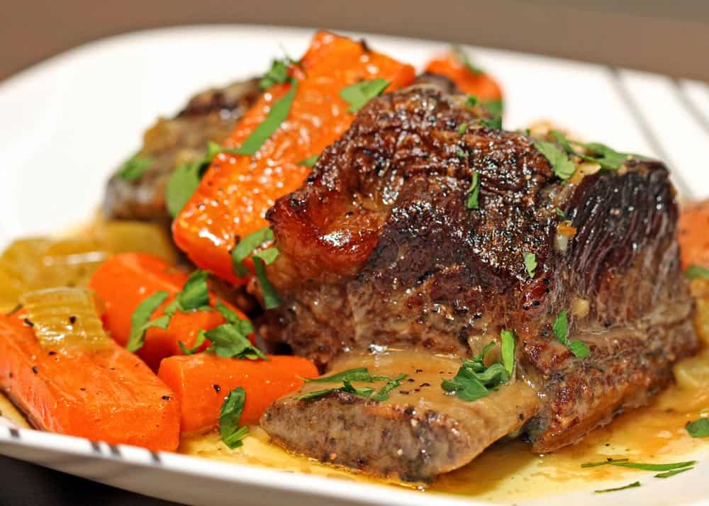 braised beef short ribs and carrots on a white dish