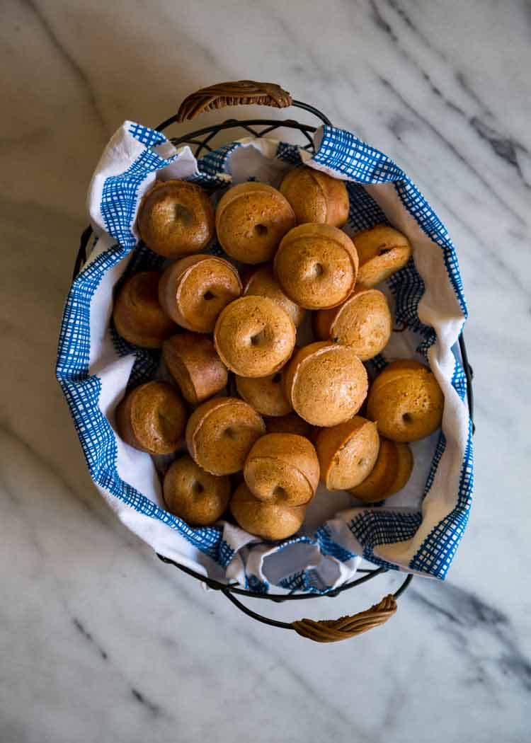 overhead of a basket full of Brazilian cheese bread with a blue and white cloth