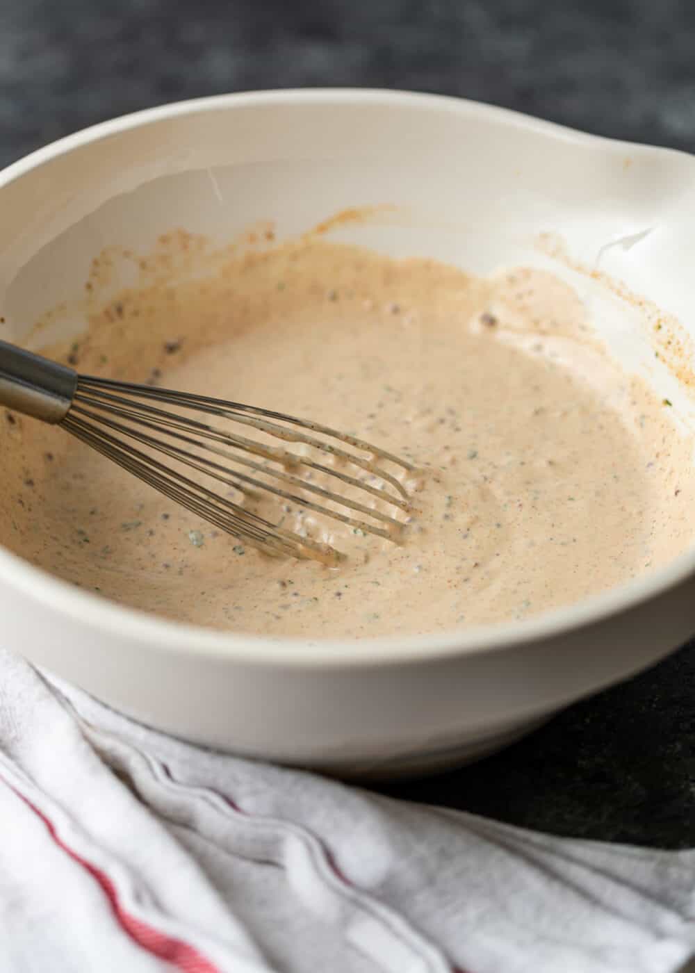 whisking together Cajun spices, mayo, capers, and mustard