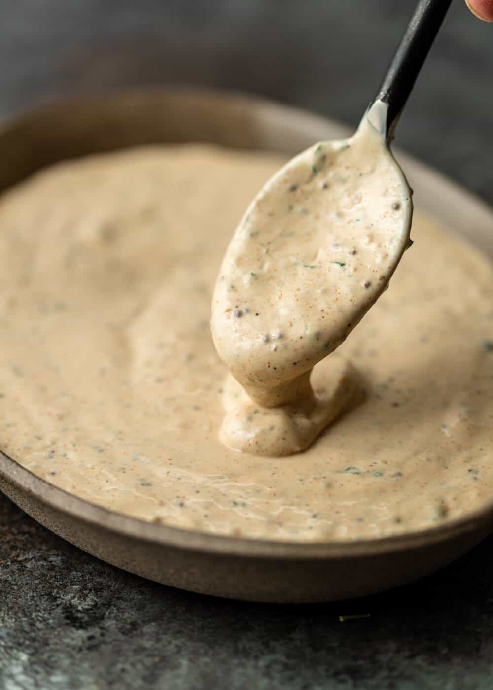 close up shot of po boy sauce dripping off spoon into bowl