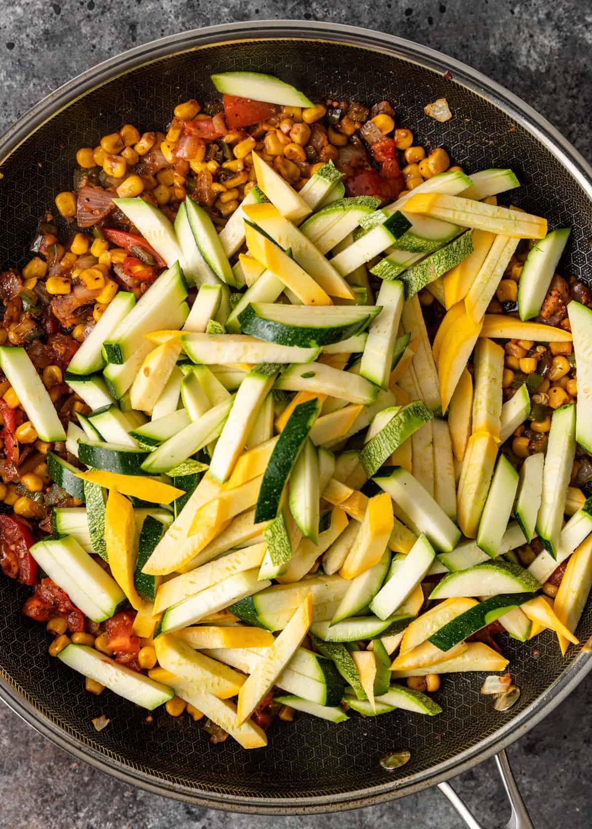 overhead: sautéing onions, peppers, corn, tomatoes, zucchini, squash, and calabacita