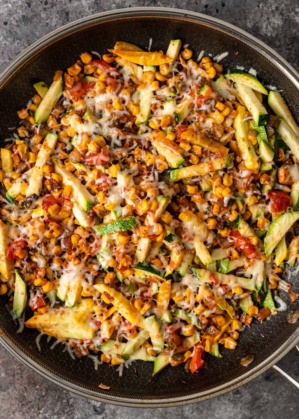 overhead: calabacita squash in a large skillet with melted shredded cheese on top