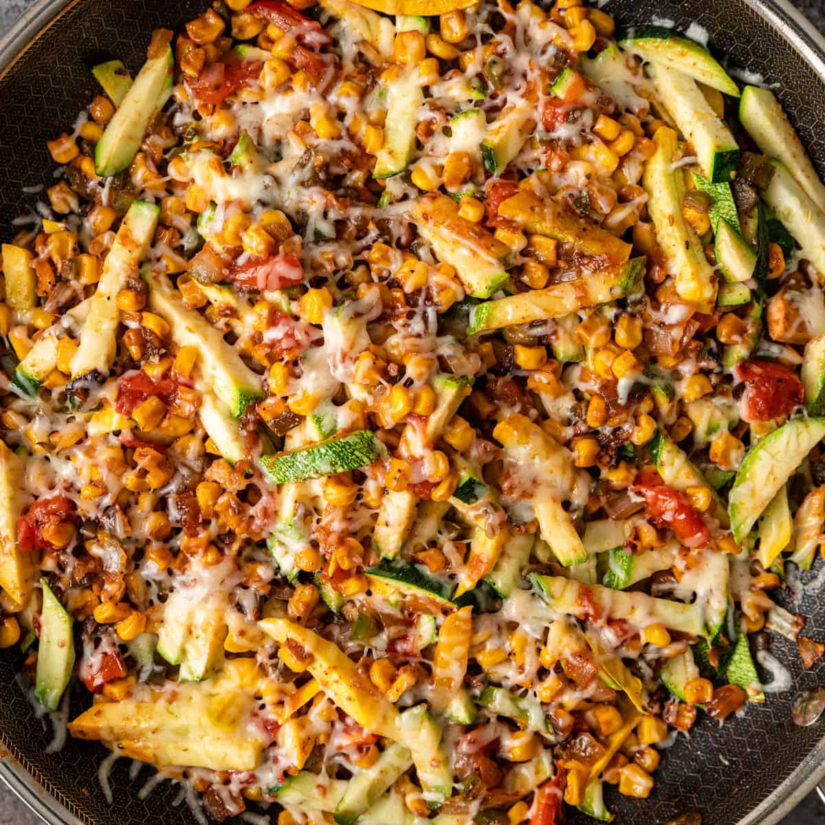 overhead: Mexican calabacitas in a large skillet with melted shredded cheese on top