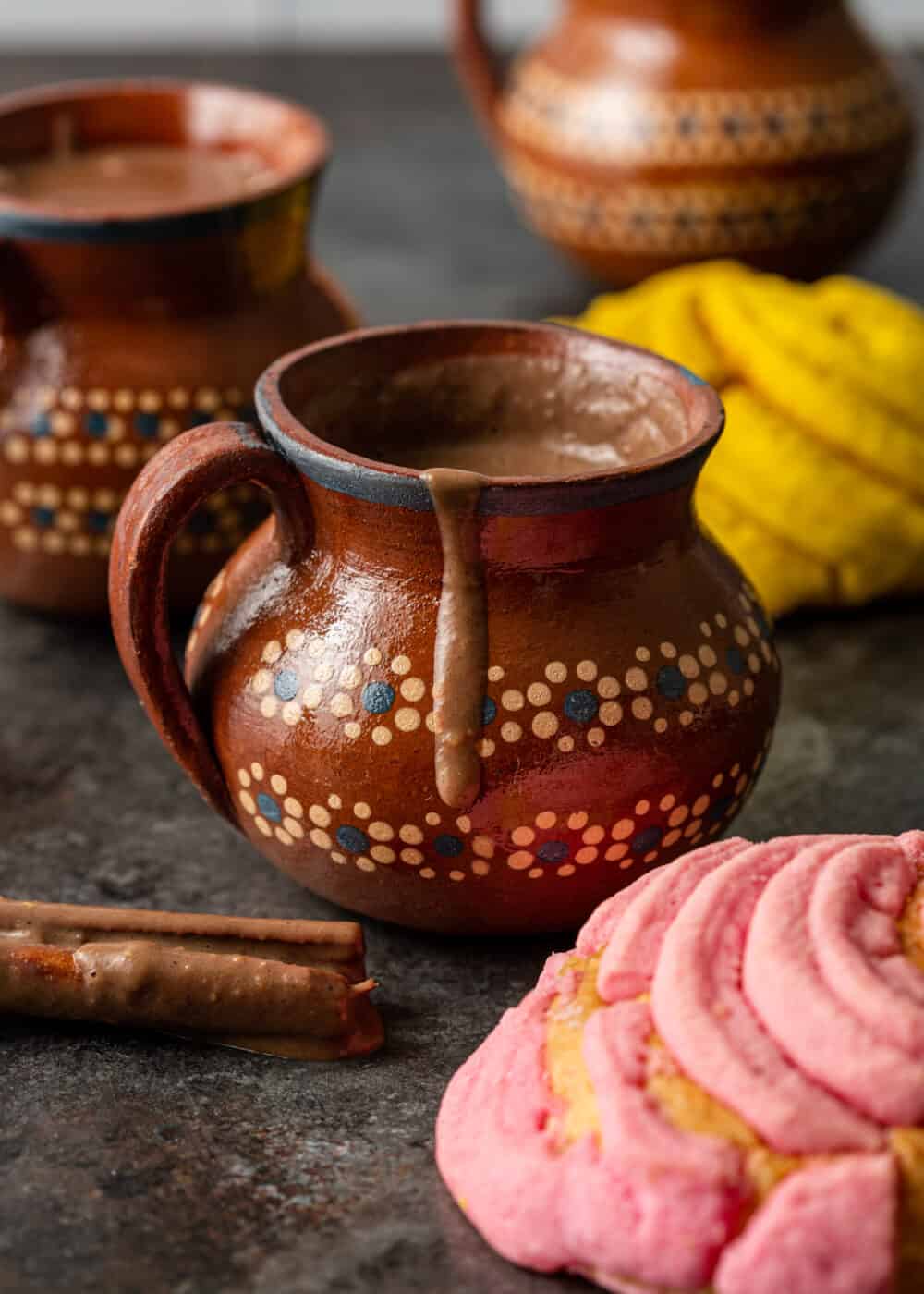 3 mugs of hot champurrado - front mug with chocolate dripping over edge