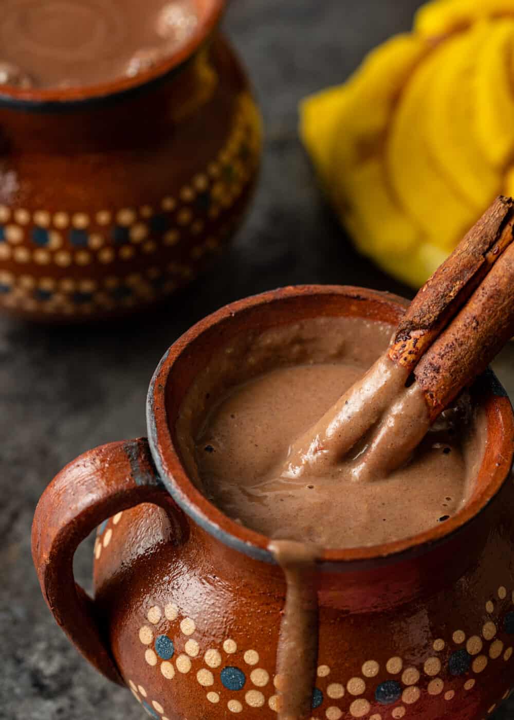 thick dark chocolate drink in mug with 2 cinnamon sticks