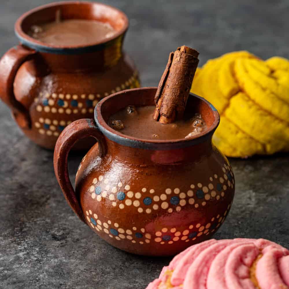 2 glazed pottery mugs filled with dark chocolate drink