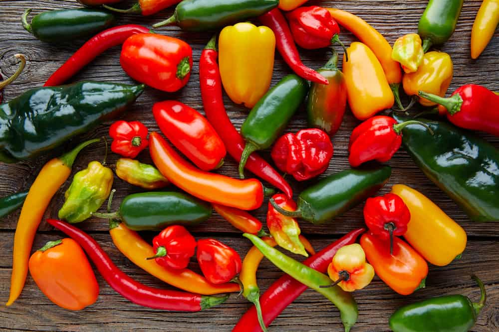 mix of fresh Mexican chili peppers on wooden bench