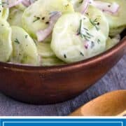 close up of creamy cucumber salad in wood bowl