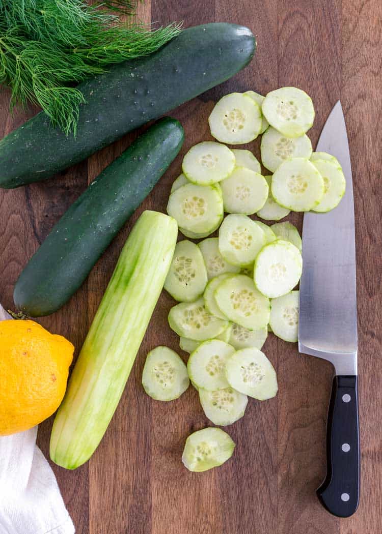 sliced cucumbers on wood board with knife