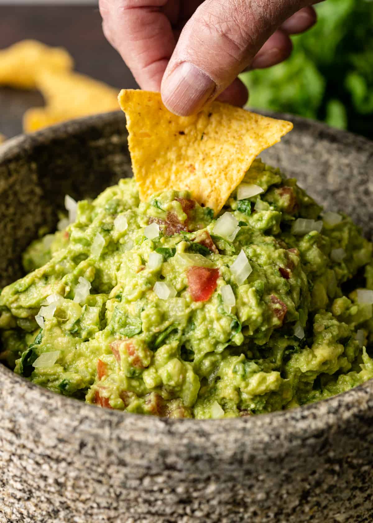 dipping a chip into Authentic Guacamole Recipe