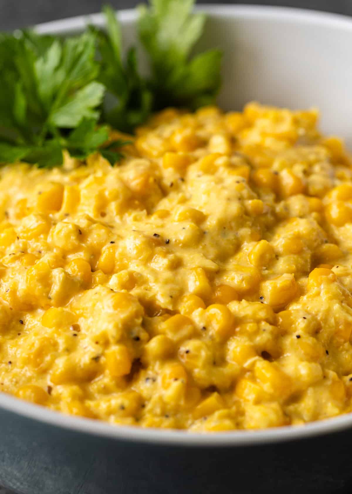 closeup: creamed corn in a bowl with fresh parsley