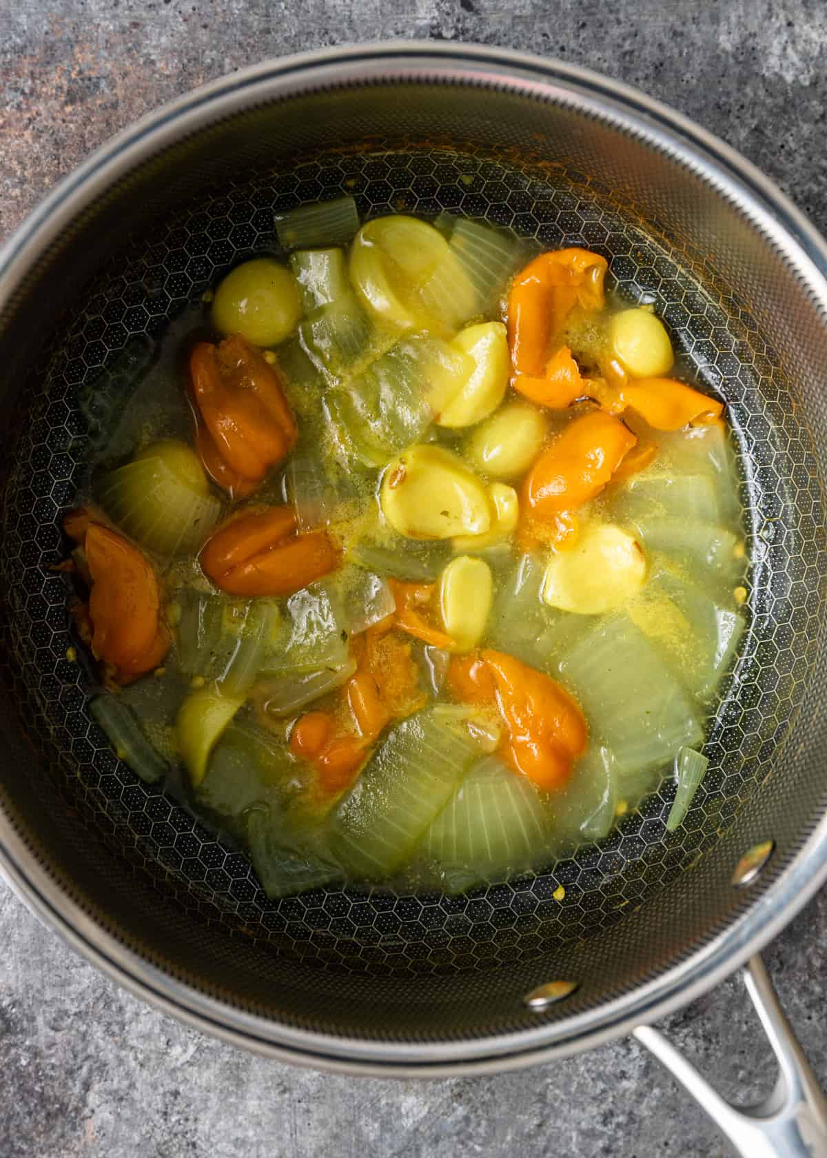 overhead: boiled onions, garlic, and peppers in a pan for creamy habanero sauce