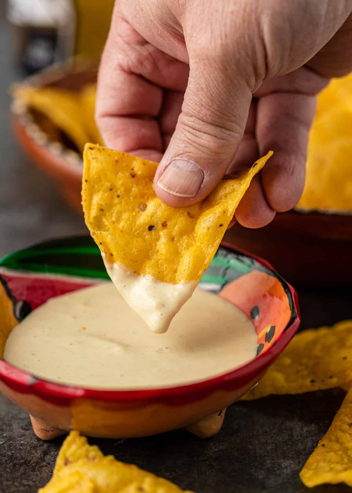 closeup: a hand dipping a tortilla chip into a small ceramic bowl of creamy habanero sauce