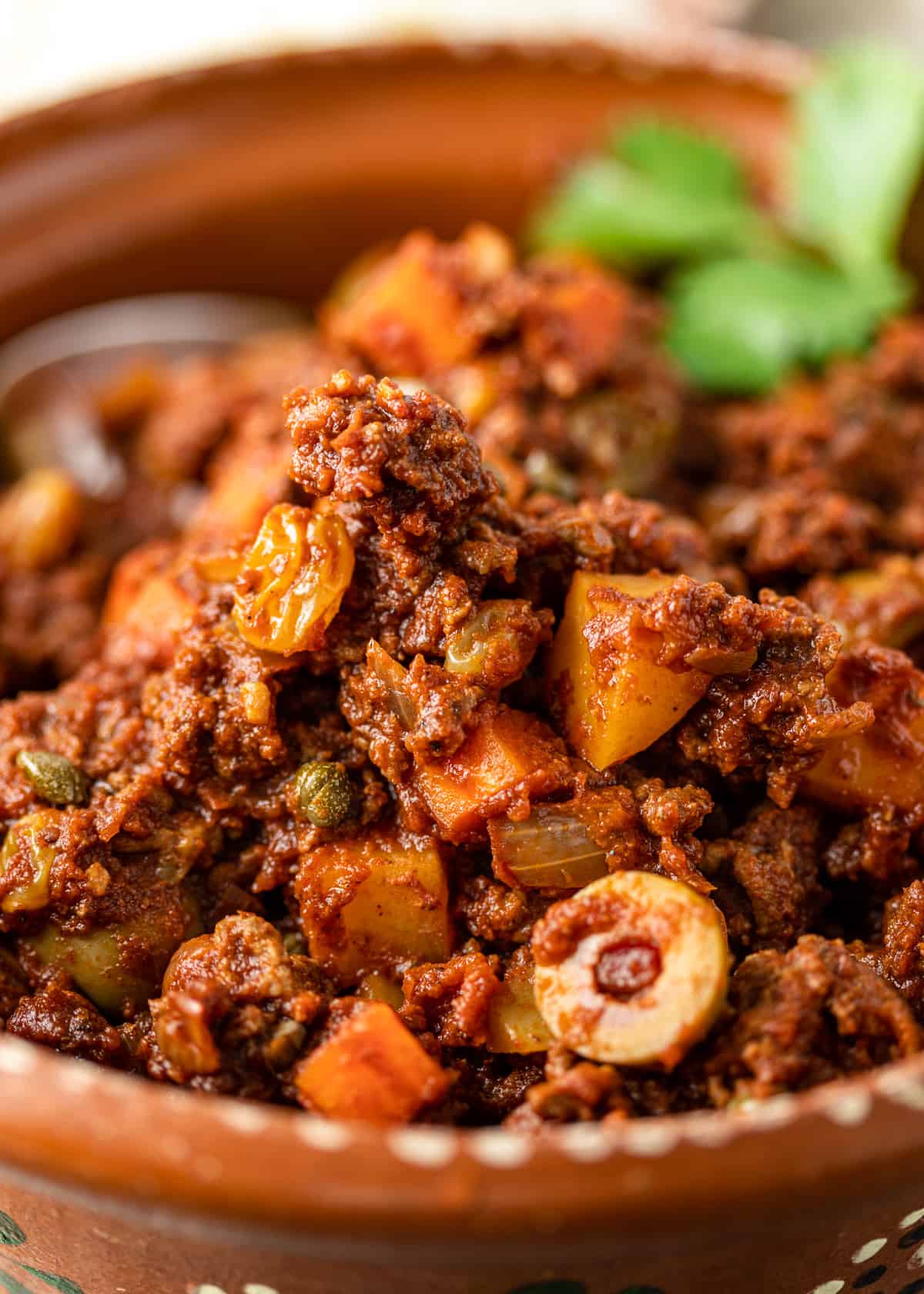 closeup: Cuban beef picadillo with olives, onions, and capers showing