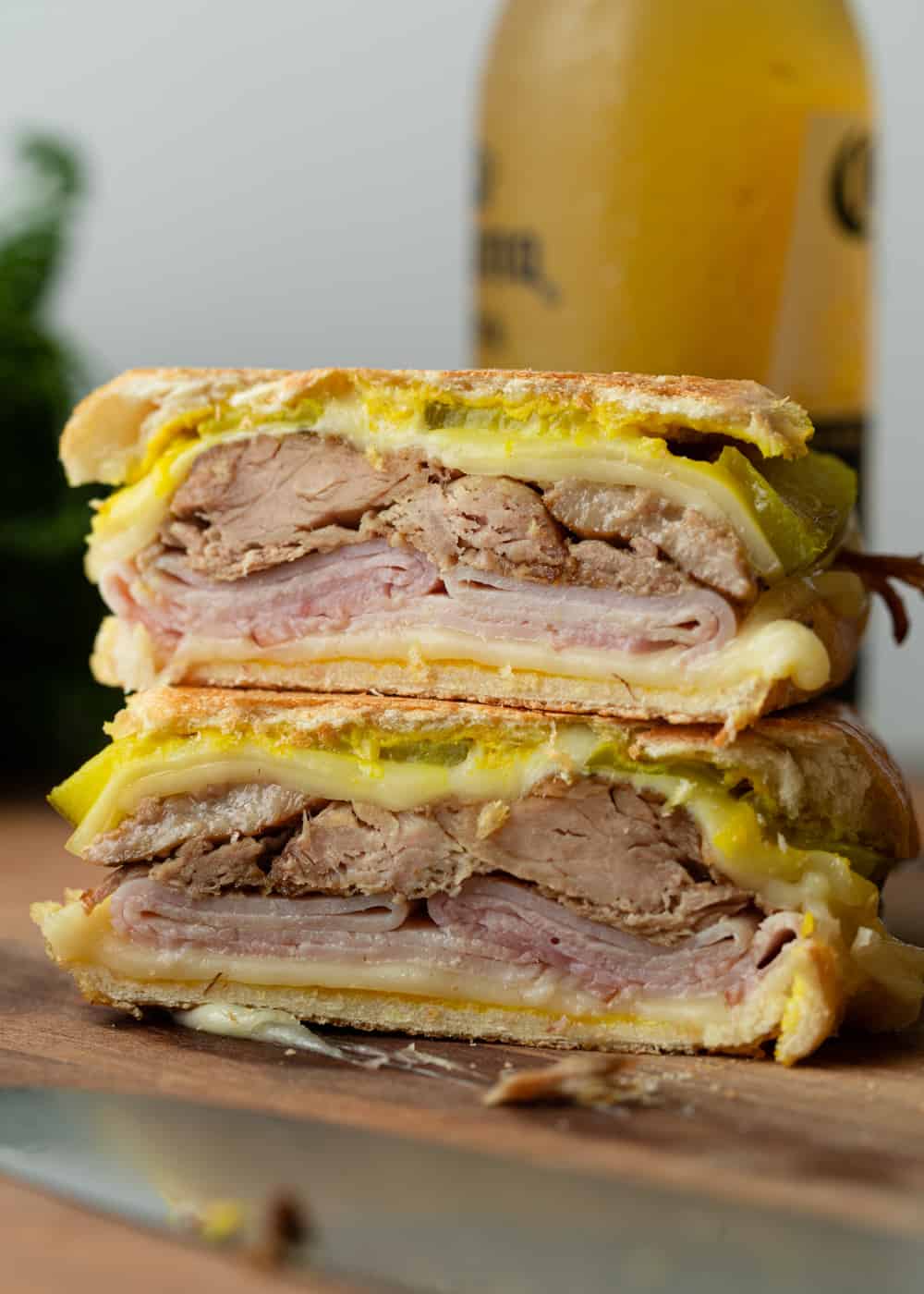 Close up image of sandwich Cubano with pork, Swiss cheese, mustard, ham and pickles.