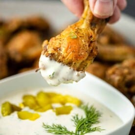 baked crispy chicken drumette being dipped into dill dipping sauce