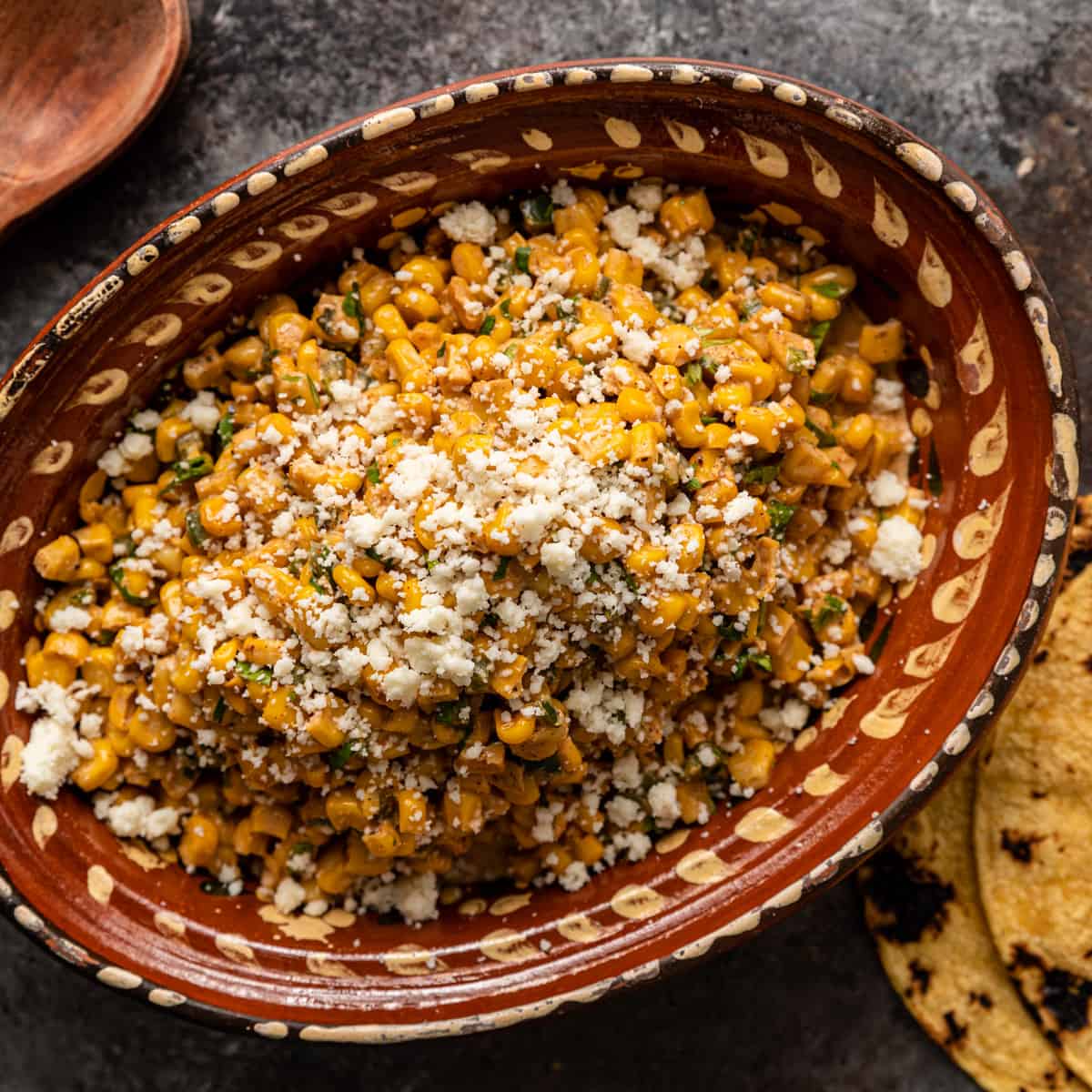 closeup overhead: a bowl of esquites Mexican street corn salad with cotija cheese on top