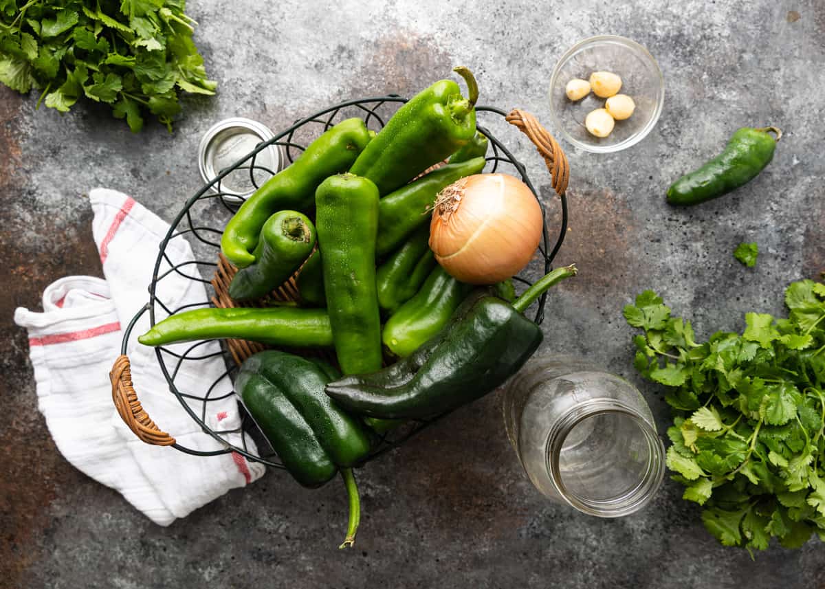 wire basket filled with fresh whole onions, peppers and garlic cloves