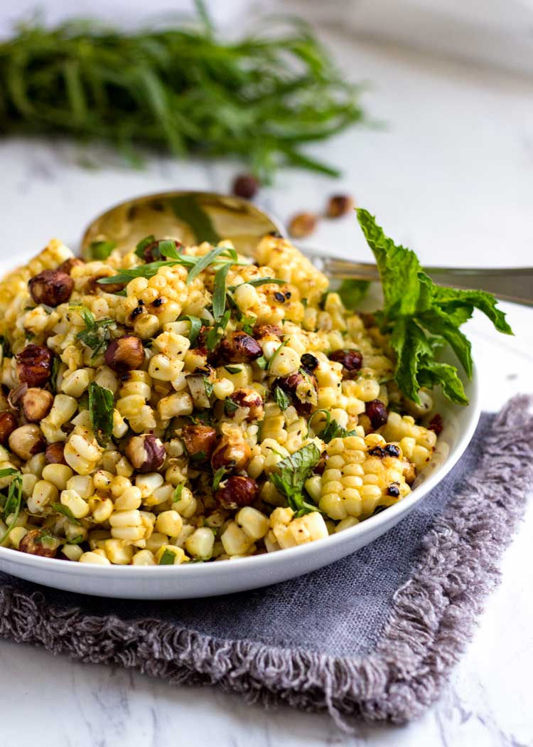 a plate of grilled corn salad with hazelnuts and fresh herbs