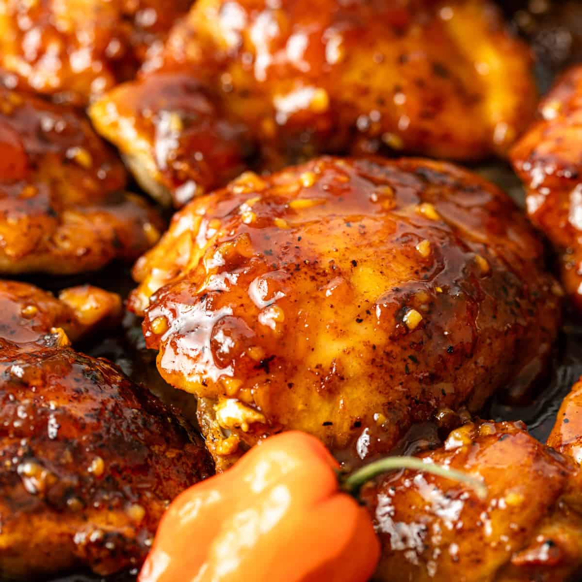 extreme closeup: habanero apricot chicken covered in a sticky sauce 