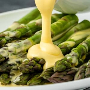 A plate of asparagus with hollandaise drizzled on top