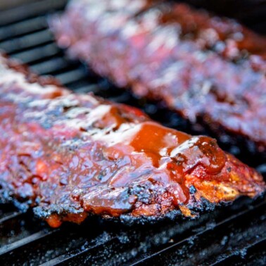 baby back ribs with bbq sauce cooking on grill