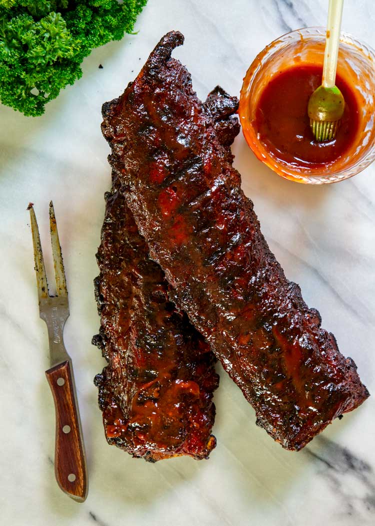 overhead image: 2 full racks of baby back ribs with barbecue sauce