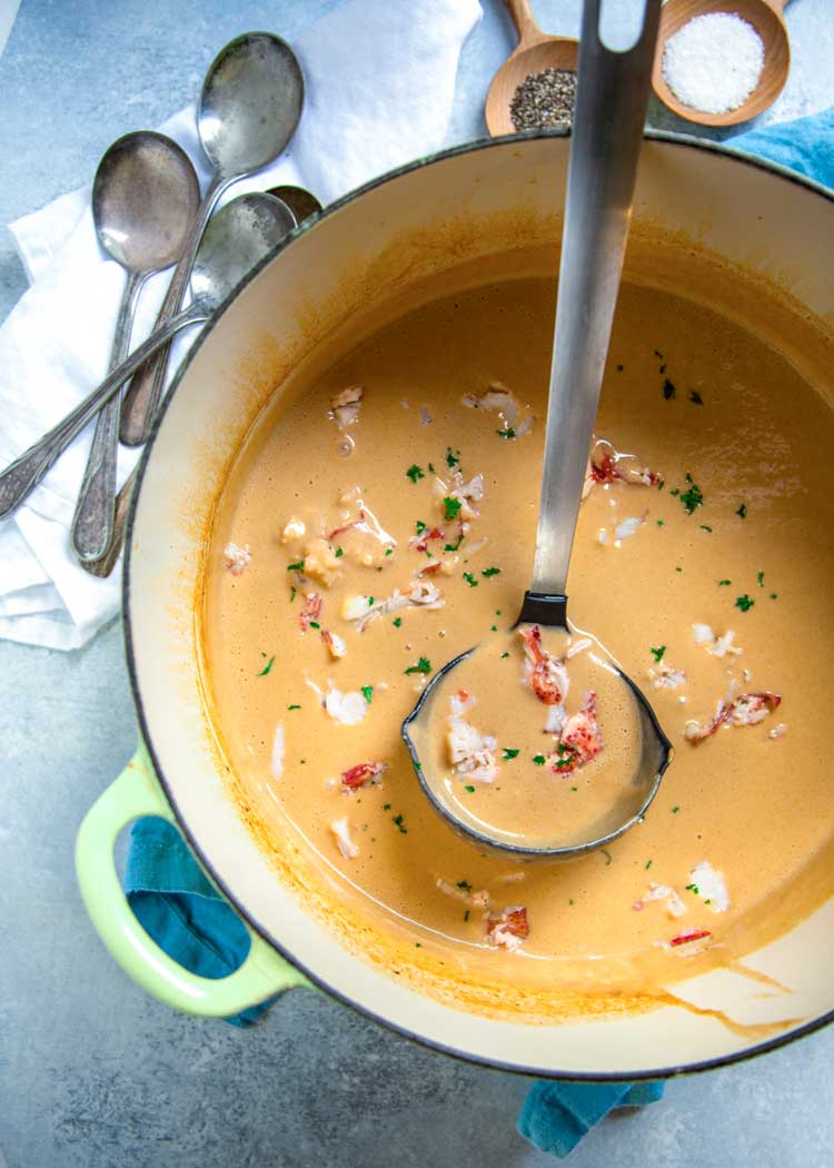 overhead: ladle of creamy seafood soup in large pot