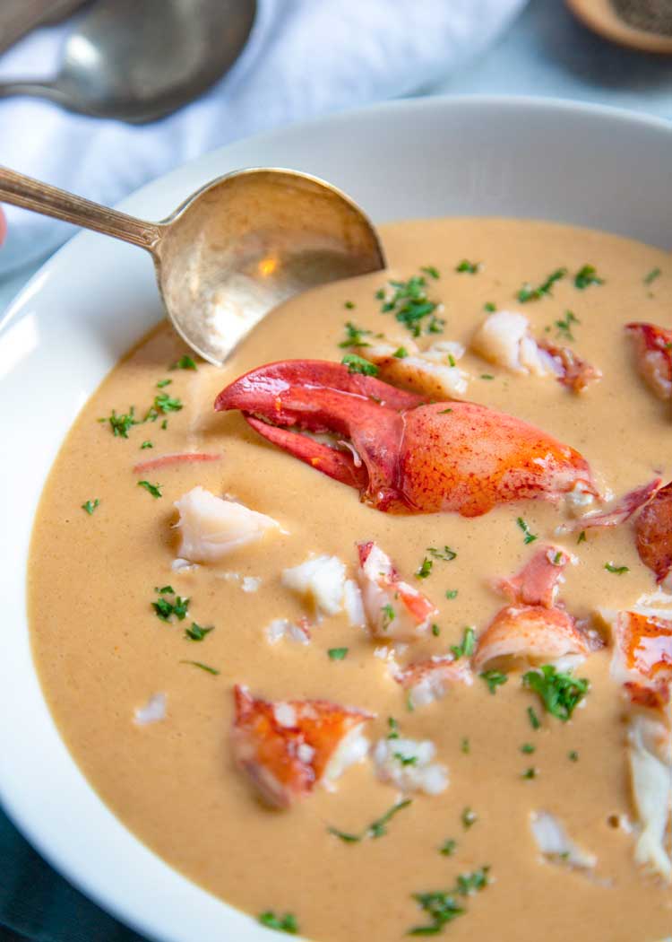 spoon dipping into bowl of homemade lobster bisque soup