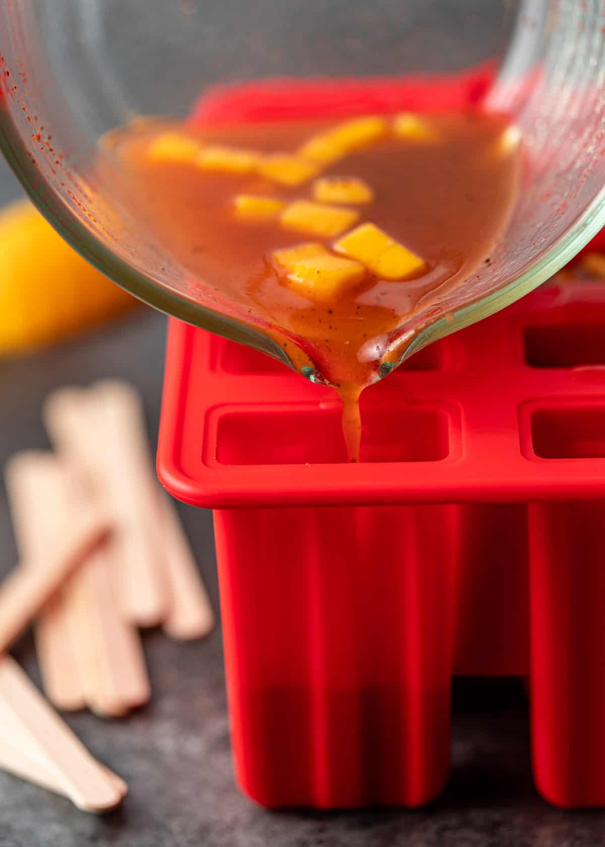pouring mango paletas into ice pop mold