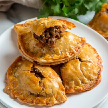 three empanadas with pie crust stacked on white plate