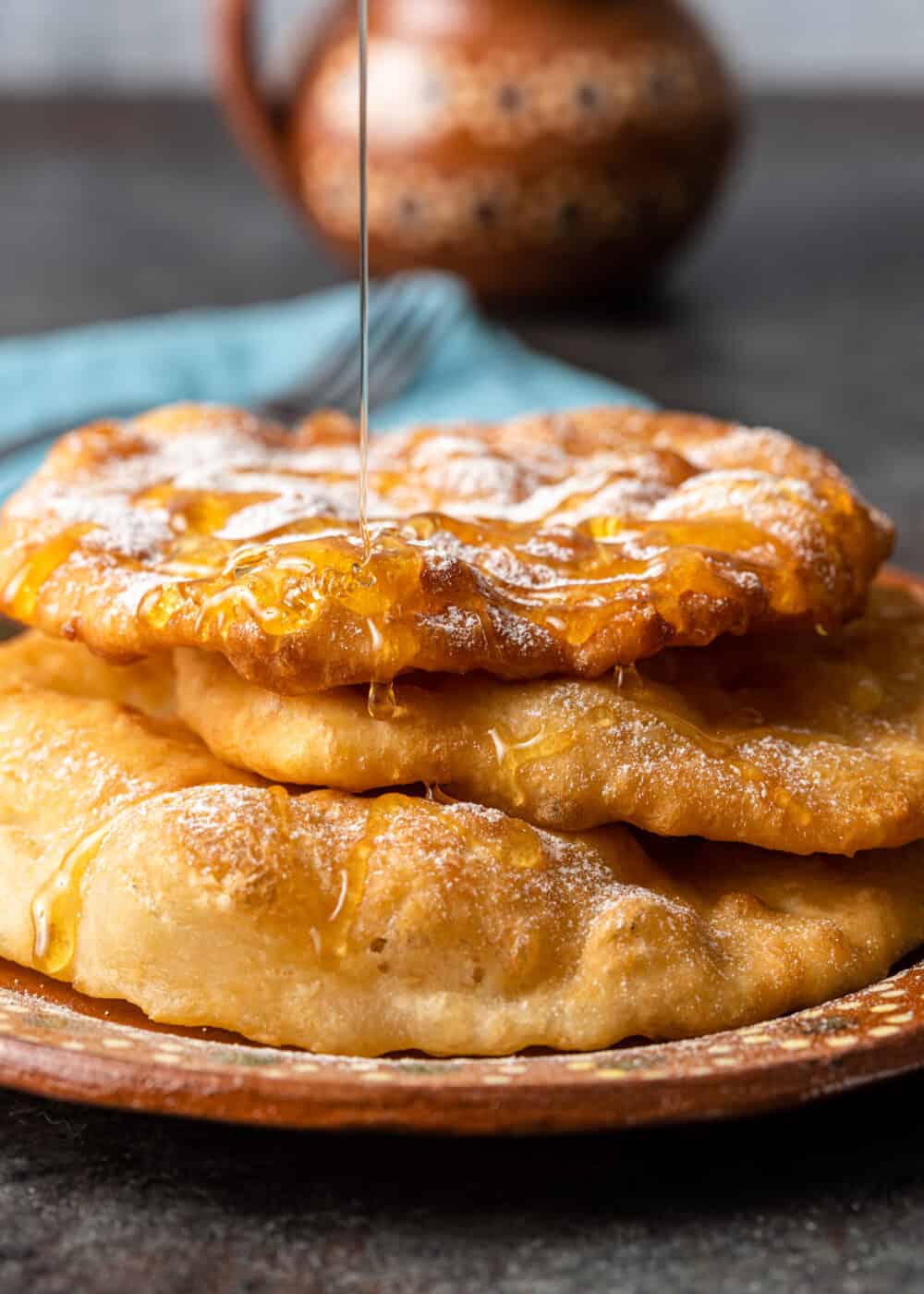 indian fry bread being drizzled in honey and powdered sugar