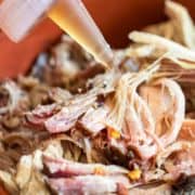 squirting North Carolina BBQ Sauce on pulled pork from bottle