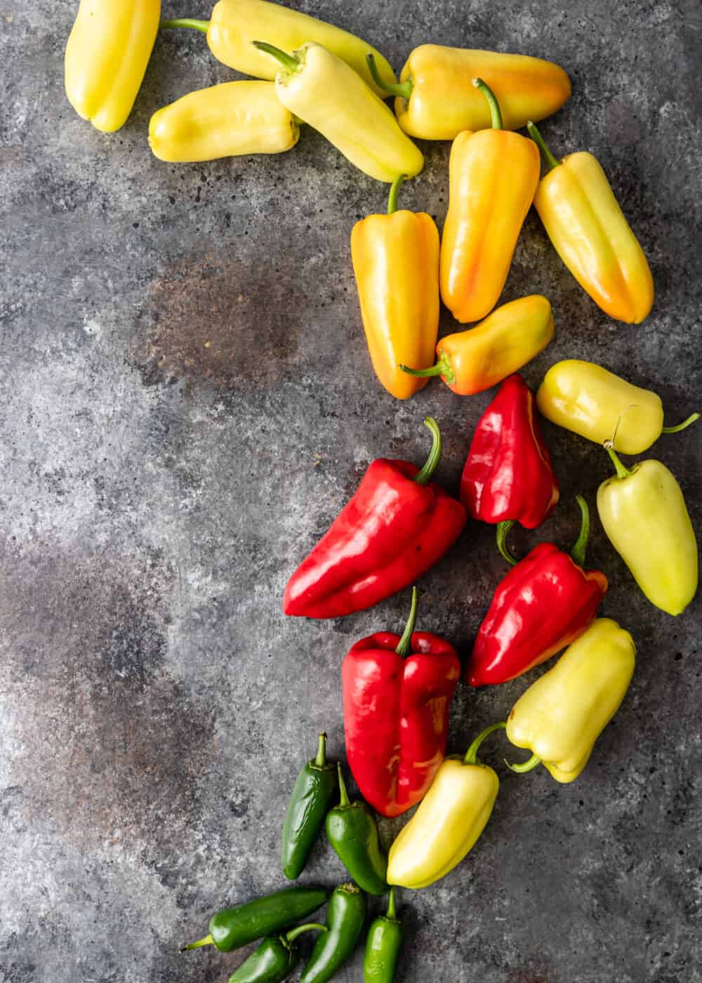 overhead; large banana peppers, red chiles and jalapenos scattered on counter top