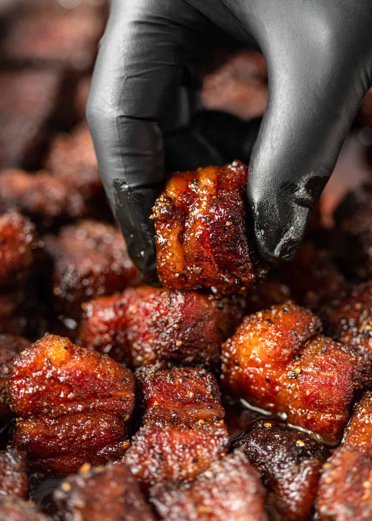 holding Pork Belly Burnt Ends in gloved hand