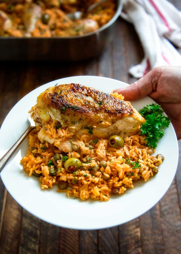 overhead: a hand holding a white plate full of arroz con pollo