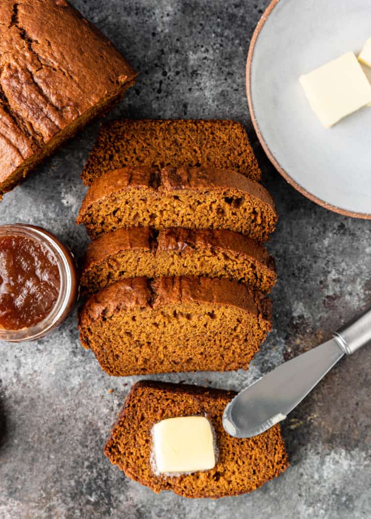 overhead: homemade banana pumpkin bread cut into slices, one slice buttered