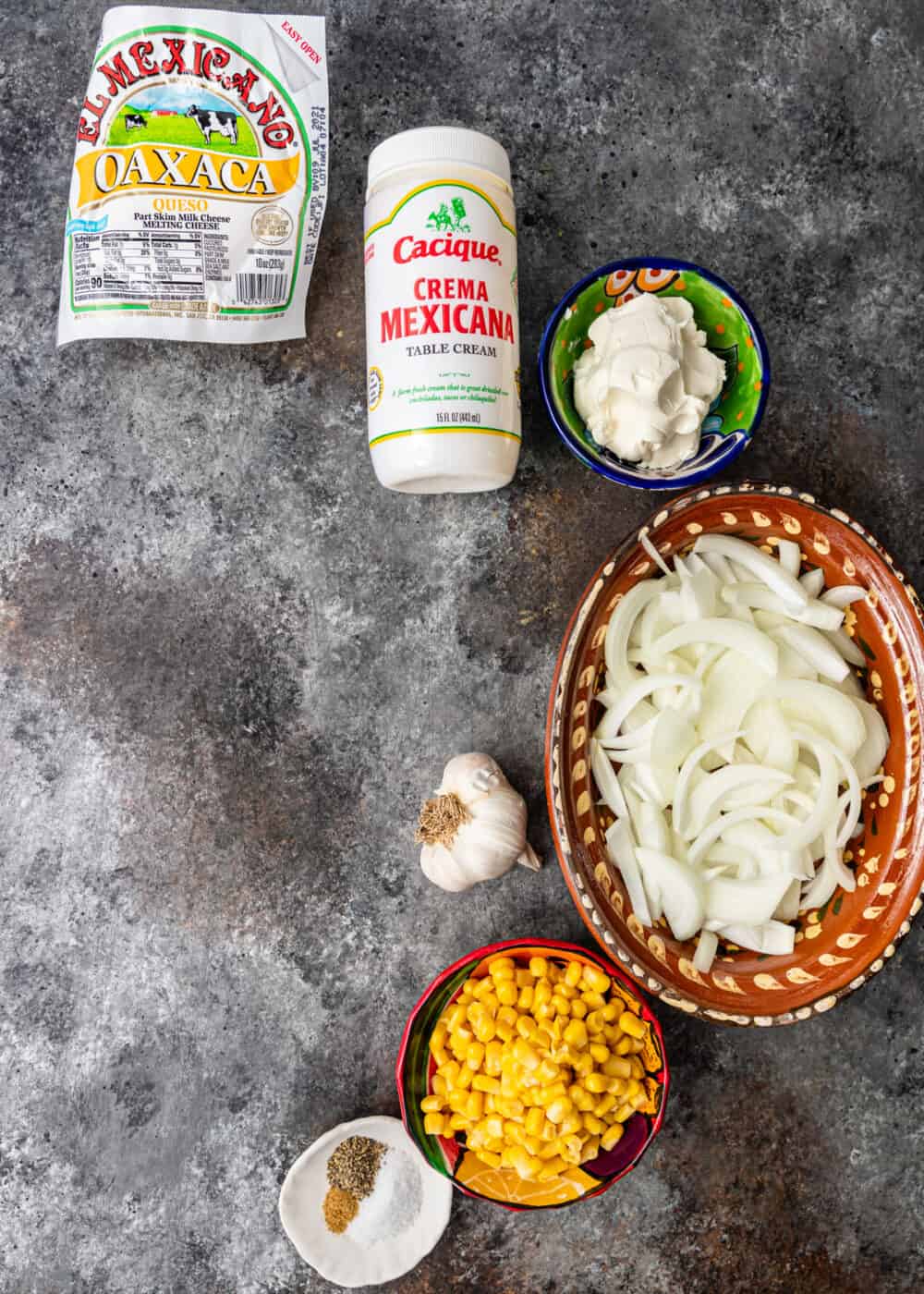 overhead image: small bowls of white onion slices, Mexican crema, corn kernels and other ingredients to make a poblano pepper recipe