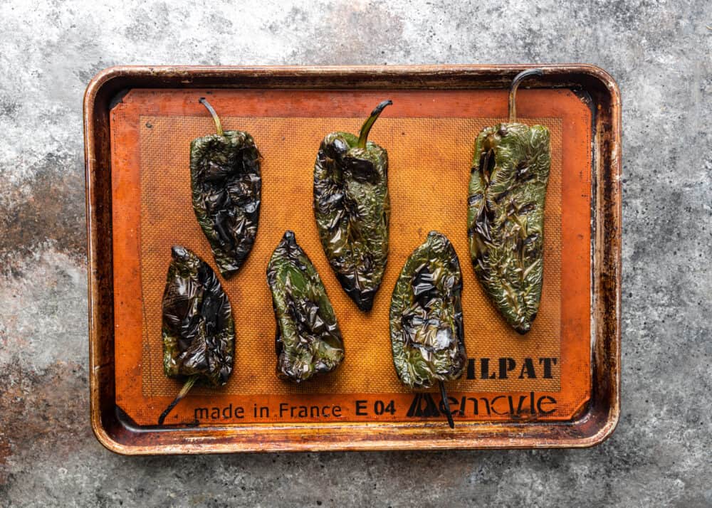 overhead image: roasted poblanos on baking sheet for making Mexican rajas con crema