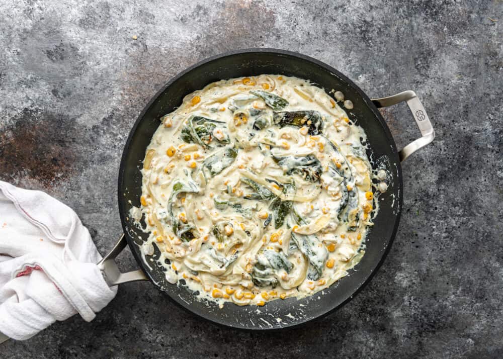 overhead image: strips of poblano chili peppers simmering in white cream sauce